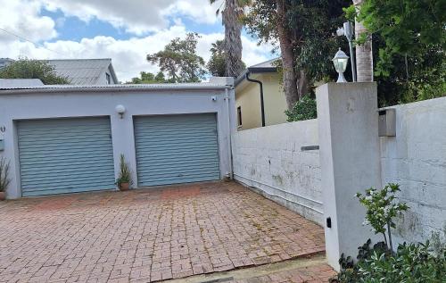a house with two garage doors and a brick driveway at House Forget Me Not in Bredasdorp