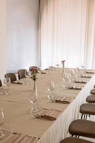 a long table with wine glasses and flowers on it at B&B HOTEL Habitat Giussano in Giussano