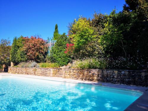 - une piscine avec un mur en pierre et des arbres dans l'établissement Maison typique avec piscine privée - 6km Sarlat, à Saint-André-dʼAllas