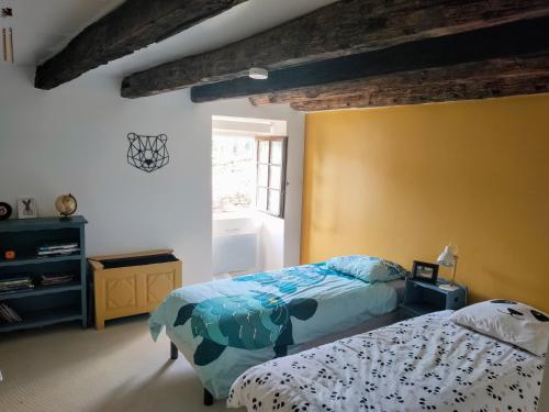 - une chambre avec 2 lits et un mur jaune dans l'établissement Maison typique avec piscine privée - 6km Sarlat, à Saint-André-dʼAllas