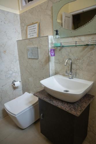 a bathroom with a sink and a toilet and a mirror at Baruah Bhavan Homestay in Guwahati
