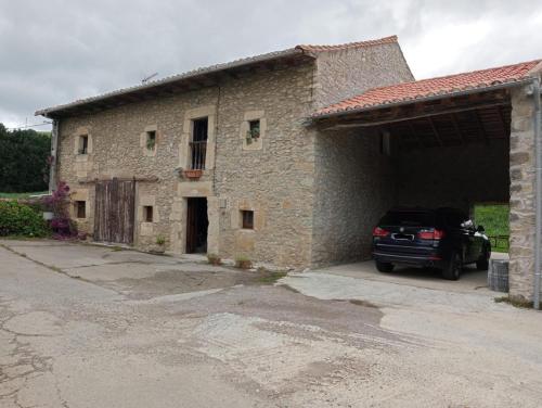 a car parked in front of a stone building at Casa rural la Venta in Bareyo