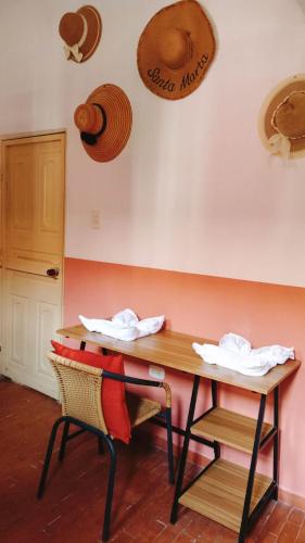 a table with a chair and a table with hats on the wall at Lotus Central Hotel in Santa Marta