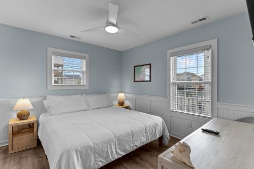 a bedroom with a white bed and two windows at Loggerhead Inn and Suites in Surf City