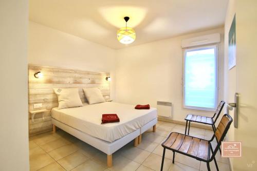 une chambre avec un grand lit blanc et une chaise dans l'établissement L'évasion seynoise, à La Seyne-sur-Mer