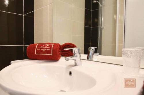un lavabo de salle de bain avec une serviette rouge posée dessus dans l'établissement L'évasion seynoise, à La Seyne-sur-Mer