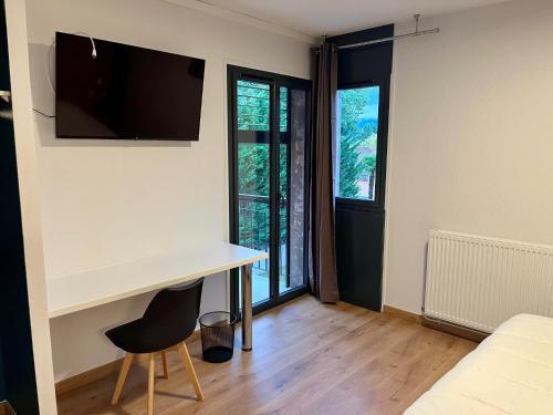 a room with a desk and a tv on the wall at Les Cimes du Mont Royal in Montréjeau