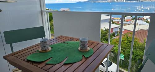 a table on a balcony with two candles on it at Studio cosy vue mer et équipé in Les Trois-Îlets