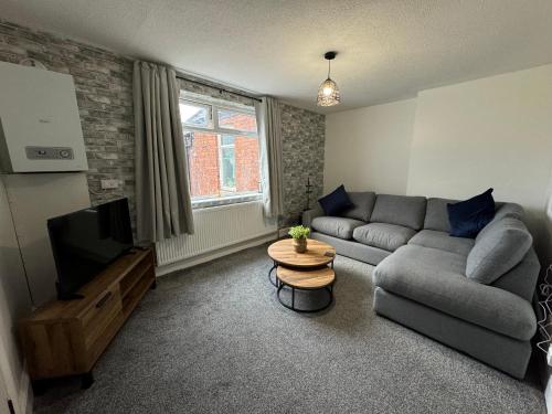 a living room with a couch and a television at Zetland House Apartment - First floor with garden and parking in Southport