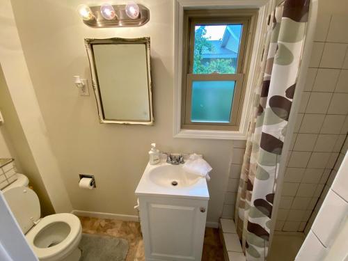 Un baño con lavabo, inodoro y espejo. en Convenient 2 Bedroom Home in TC, en Traverse City
