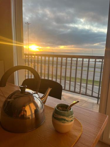 a tea kettle on a table with a view of a balcony at Amanecer frente al mar in Mar del Plata
