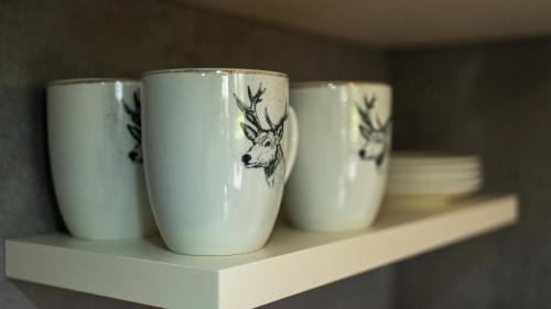 four white cups sitting on a shelf at Tiroler Alpblick Appartements in Ehrwald