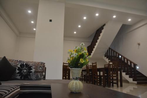 a vase with flowers on a table in a living room at Sea View Tourist Inn in Tangalle