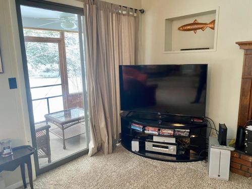 a living room with a large flat screen television at Secluded Au Sable River Home in Grayling