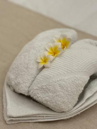 Dos toallas blancas con flores amarillas y blancas. en Private Villa - New! Casa Luna Jimbaran 3BR Indonesian - Greek Villa, en Jimbaran