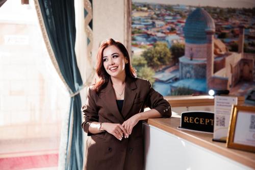 a woman in a suit standing at a counter at BEX SUENO HOTEL in Samarkand
