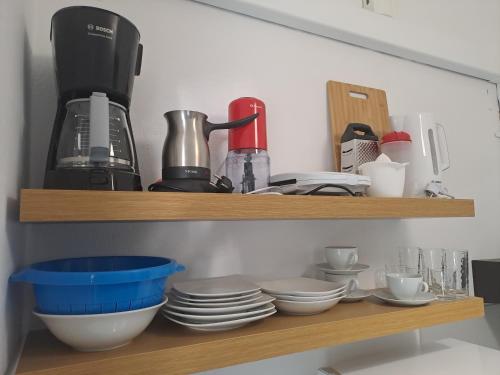 a shelf with bowls and plates and a coffee maker at Studios Αποστόλης Selianitika in Aígio