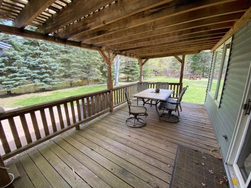 a wooden deck with a table and chairs on it at Secluded Au Sable River Home in Grayling