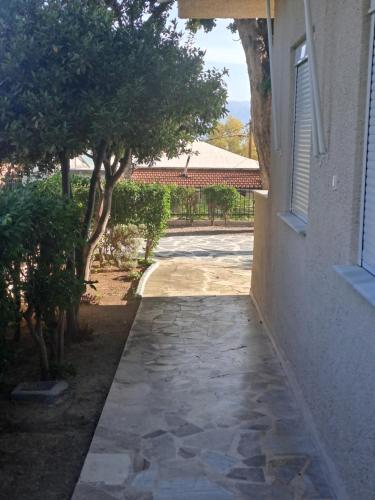a walkway next to a building with trees and a window at Studios Αποστόλης Selianitika in Aígio