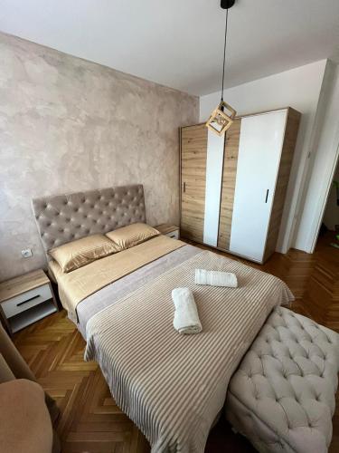 a bedroom with a large bed and a chair at Apartment Aleksandrija in Niš
