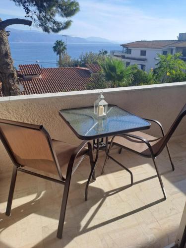 a glass table and chairs on a balcony with a view of the ocean at Studios Αποστόλης Selianitika in Aígio