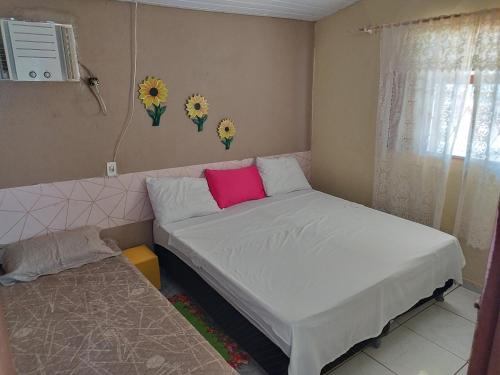 a small bedroom with a bed with a pink pillow at Casa Pedacinho do Céu in Estivado