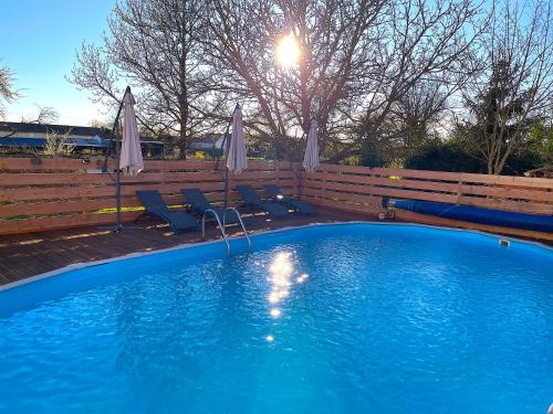 a blue swimming pool with chairs and umbrellas at Le Gîte des Jonquilles up to 12 People 6 Bedrooms in Melleran
