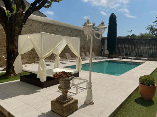 une piscine avec une tente, une table et un pôle de lumière dans l'établissement Maison de maître Les toiles à Elise, à Saint-Geniès-de-Comolas