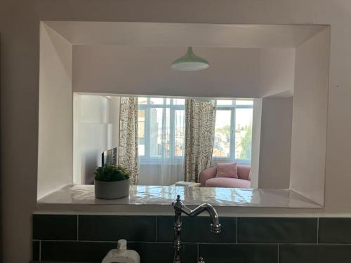 a mirror above a sink in a kitchen with a pink chair at ALICE Daire in Konak