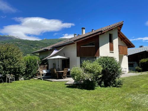 une maison avec une cour dotée d'une pelouse dans l'établissement Maison au cœur de la vallée de Haute-Tarentaise, à La Plagne Tarentaise