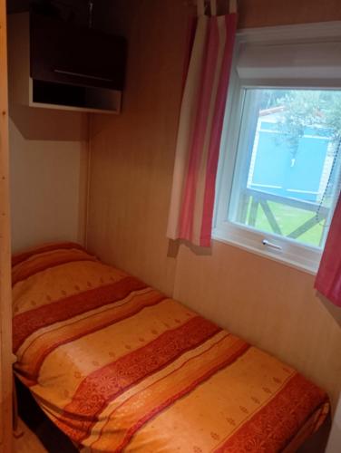 - une petite chambre avec une fenêtre et 2 lits dans l'établissement Chalet de vacances 5 couchages, à Saint-Cyr-en-Talmondais
