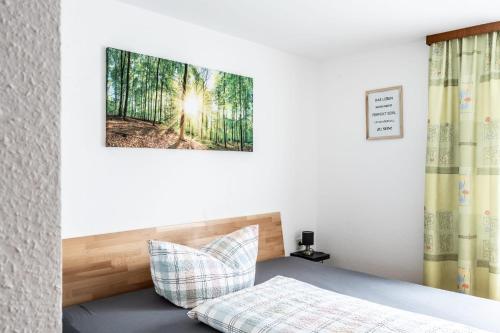 a bedroom with a bed and a picture of a forest at Pension Stein in Göfis