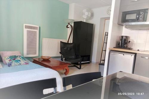 une chambre avec un lit et une chaise et une cuisine dans l'établissement La cahute, studio avec cour extérieure, à Montauban