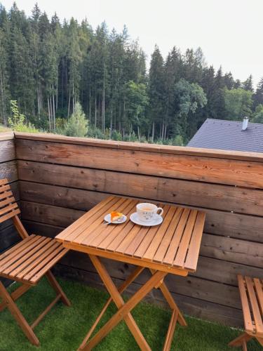 a wooden table with a cup of coffee on a patio at Slunečný apartmán in Cerny Dul