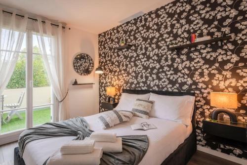 a bedroom with a bed with a floral accent wall at Agapé by Kleidos -Disney à 10min, T2 , 4P, Parking gratuit et terrasse in Magny-le-Hongre