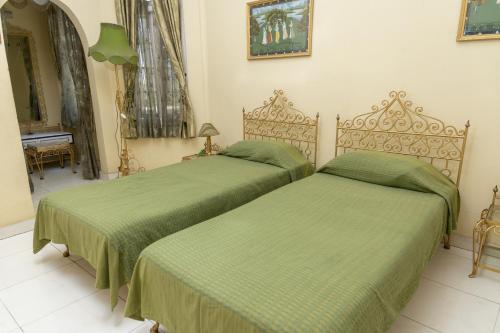 two beds in a room with green sheets at Baruah Bhavan Homestay in Guwahati
