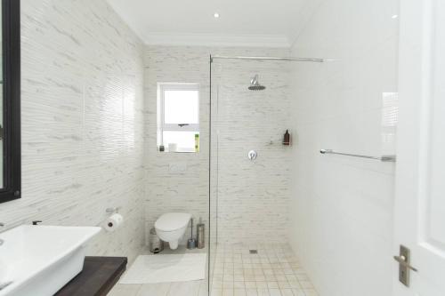 een badkamer met een douche, een toilet en een wastafel bij The Nautical Nook in Gqeberha