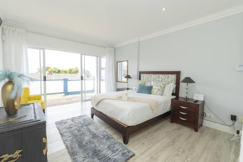 een witte slaapkamer met een bed en een raam bij The Nautical Nook in Gqeberha