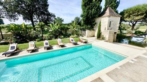 une piscine avec des chaises longues et une maison dans l'établissement Château de Lafont Suites, à Saint-Vivien