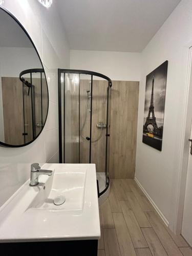 a bathroom with a sink and a shower with a mirror at Apartament Skarbowa Star in Leszno