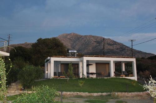 a white house with a mountain in the background at Boutique apartments Myesis in Samothráki
