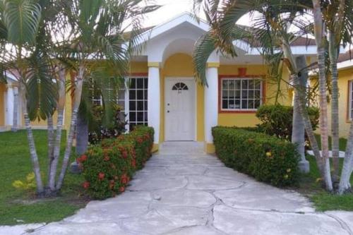 a yellow house with palm trees and a driveway at casa de playa dentro del Complejo Turistico Palma Real in El Corazón
