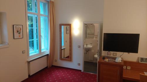 a hotel room with a television and a bathroom at die Villa, Zimmer 24, DZ in Leverkusen