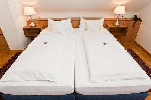 two beds in a room with two lamps at Hotel garni Schacherer in Müllheim