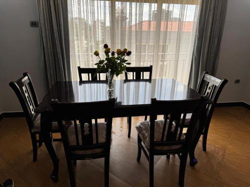 a dining room table with chairs and a vase of flowers at Family apartment Prime location and easy access 1 in Addis Ababa