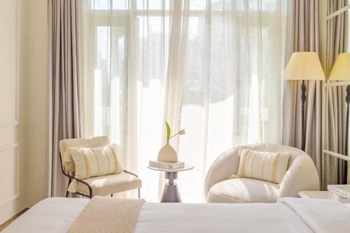 a bedroom with a bed and two chairs and a window at Keypad Hotel - Nhân Hòa in Hanoi