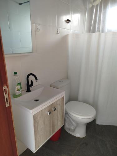 a bathroom with a white toilet and a sink at Aconchego da Montanha in Garopaba