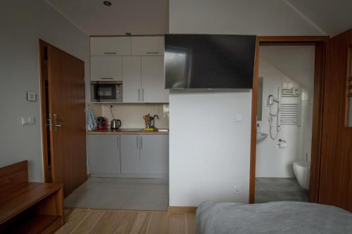 a kitchen with white cabinets and a bed in a room at Zielona Ostoja - Pokoje i Apartamenty in Nowa Sarzyna