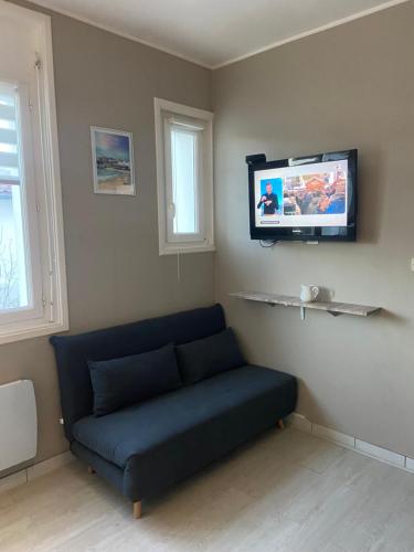 un salon avec un canapé et une télévision au mur dans l'établissement Studio 300m de la plage, à Royan