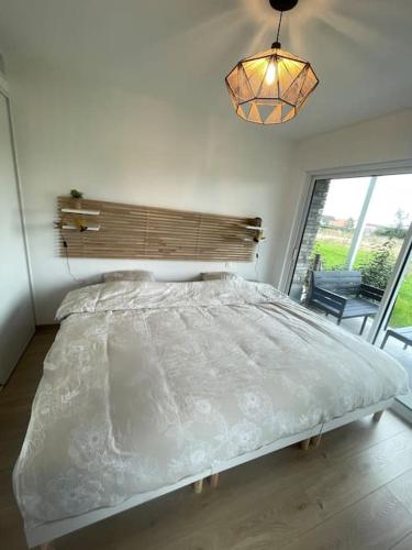 une chambre avec un grand lit et un lustre dans l'établissement L'Escale Paisible, entre dunes et plages, à Camiers